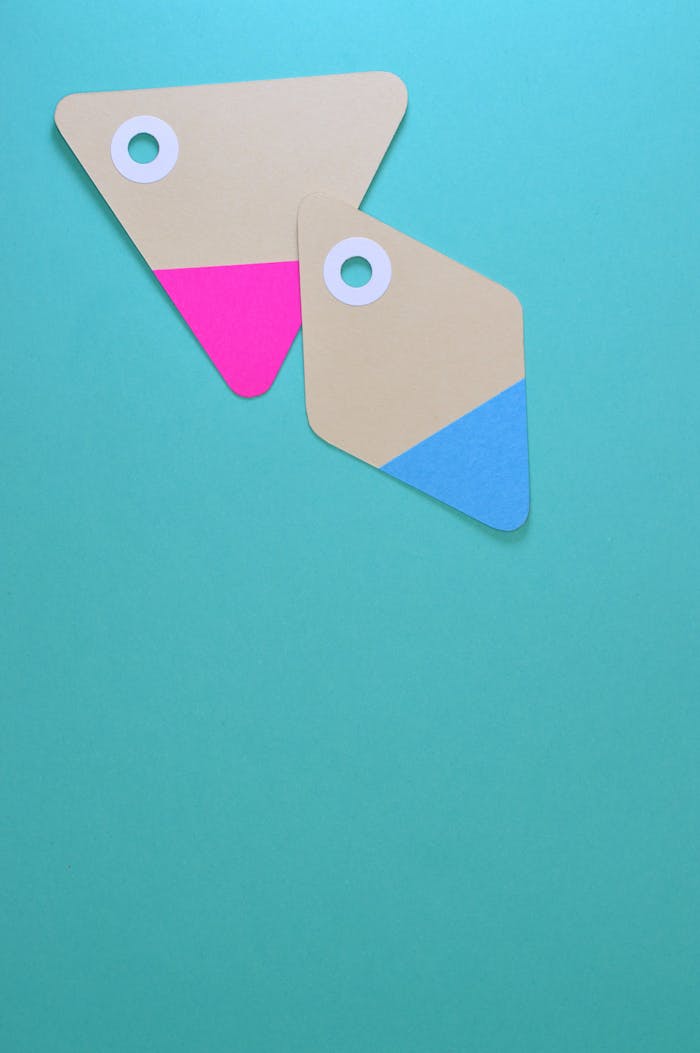 creative-03 Two colorful paper tags with holes on a teal background. Ideal for design and marketing concepts.